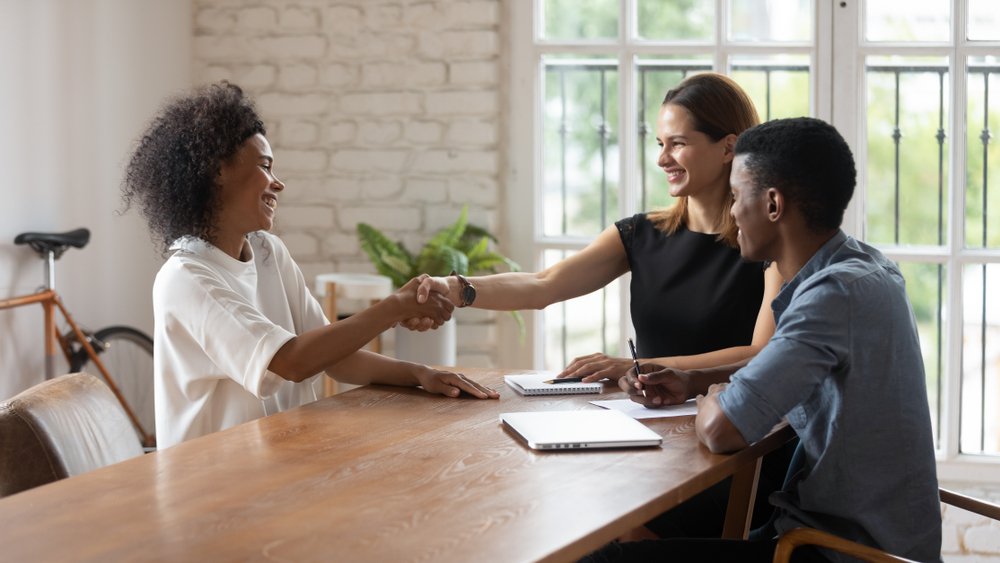 Young woman candidate shake hand with staffing agencies manager at office meeting.