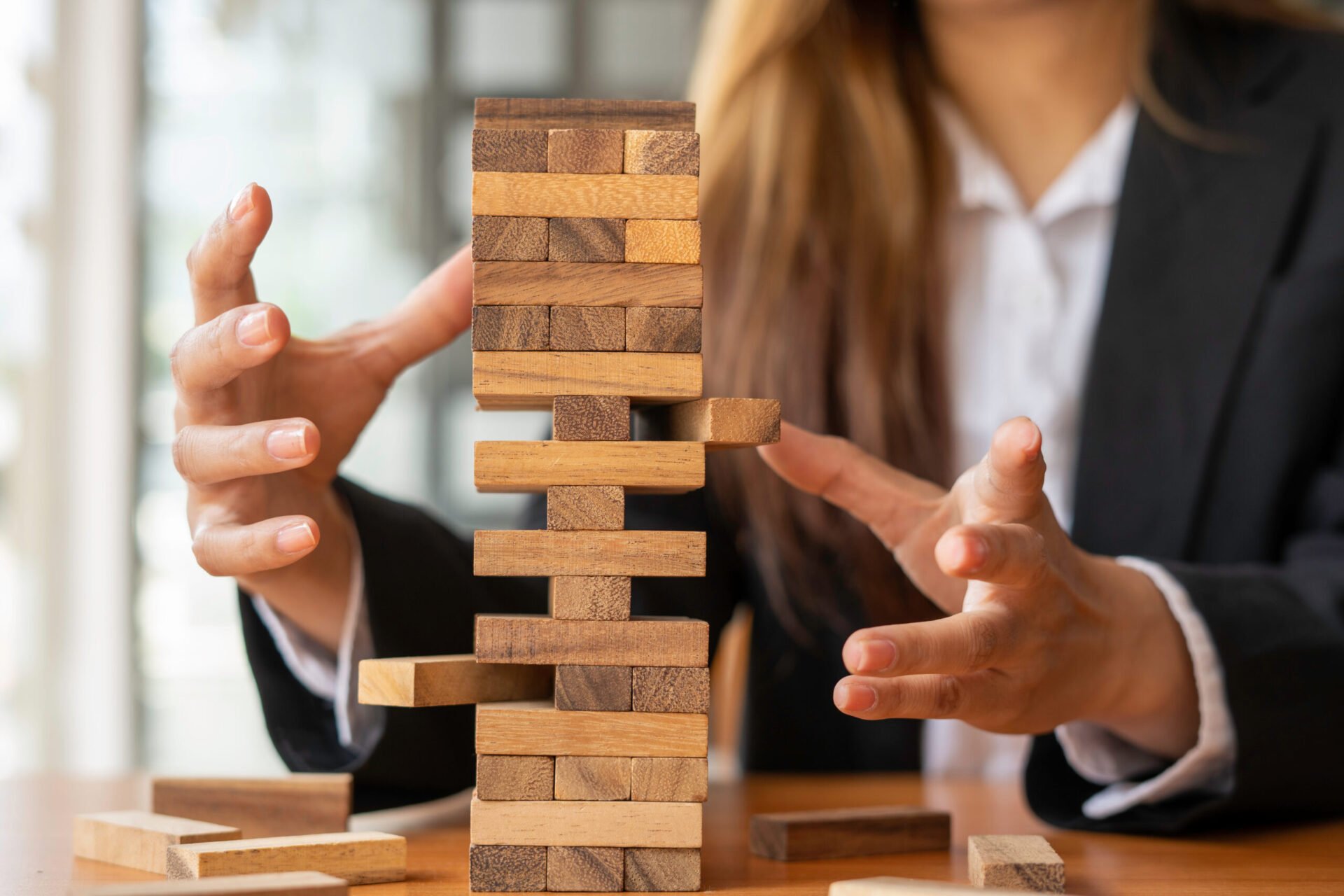 businesswoman holds her hand on a wooden block with a weak base. It is like a business risk mitigation strategy.