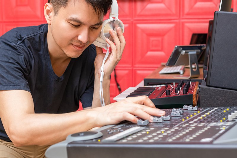 A person wearing headphones and working on a sound console.