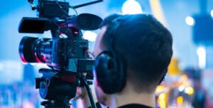 A videographer wearing headphones and shooting something