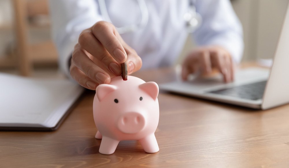 Doctor putting a coin into a piggy bank