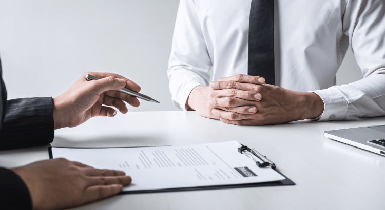 Client or agent are sitting on the table and signing papers.