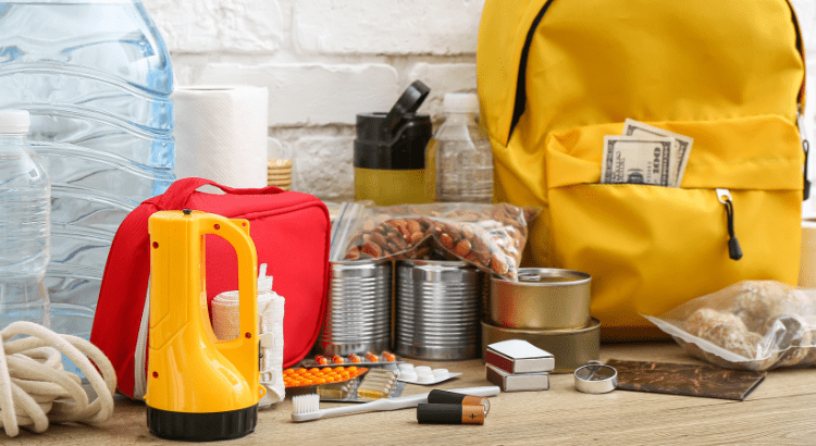 A yellow bag with popping out some dollers and torch, matchbox, toothbrush, batteries, medicines, water bottle or some dry fruits kept all together.